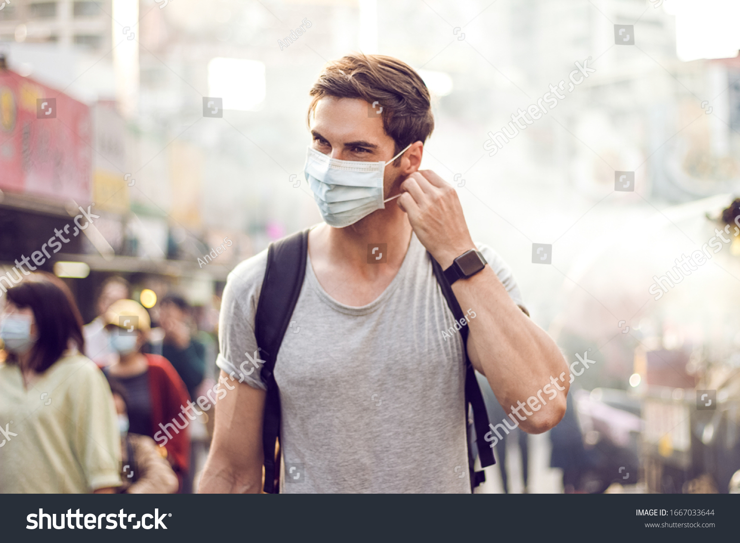 Young handsome man walking around night market in Taipei with backpack and wearing a face pollution mask to protect himself from the coronavirus. #1667033644