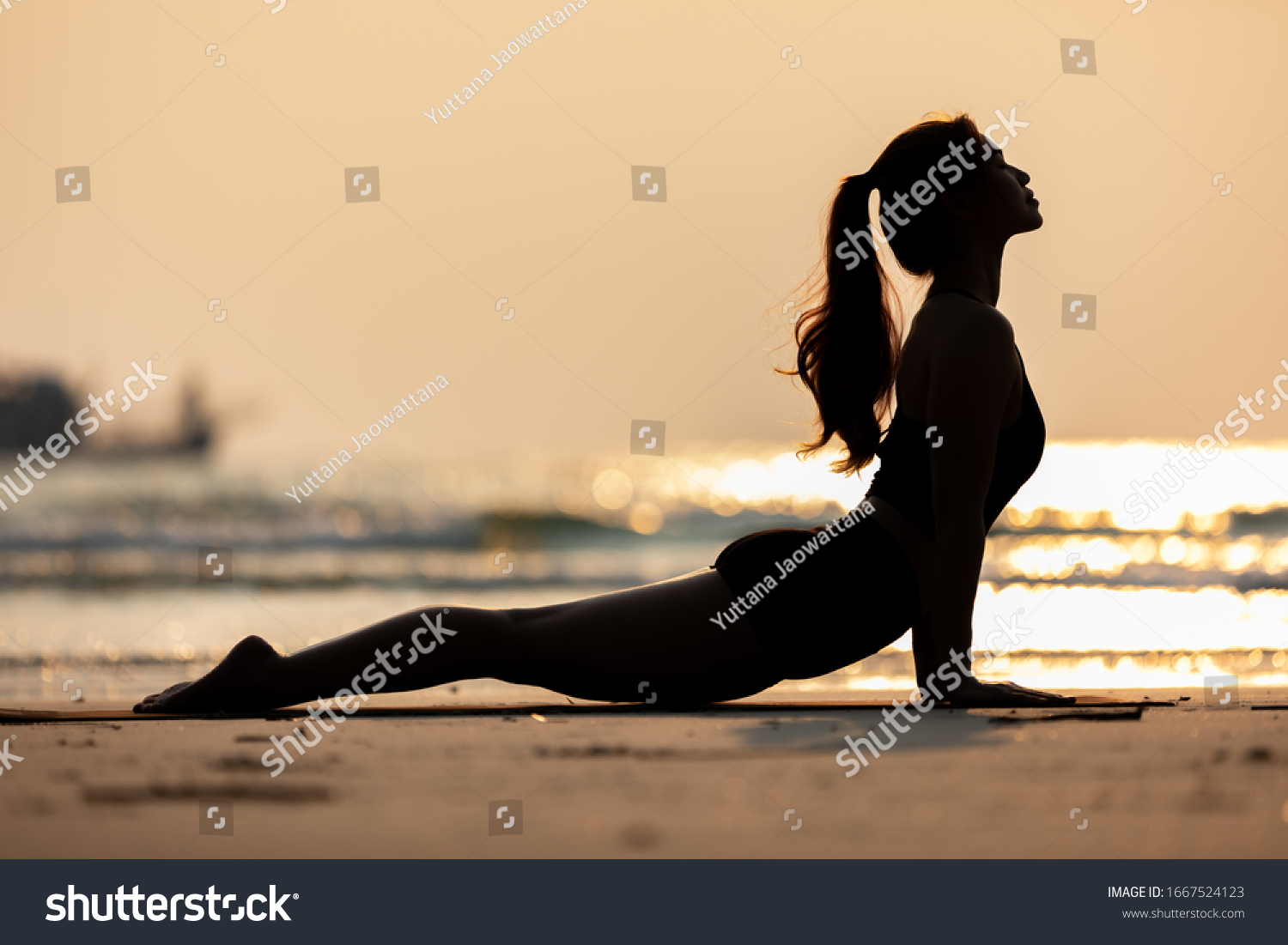 Silhouette of Athletic Asian young woman practice Cobra Pose on the sand and beach with sunset beautiful sea in Tropical island,Feeling comfortable and relax in holiday,Vacations Yoga Concept #1667524123