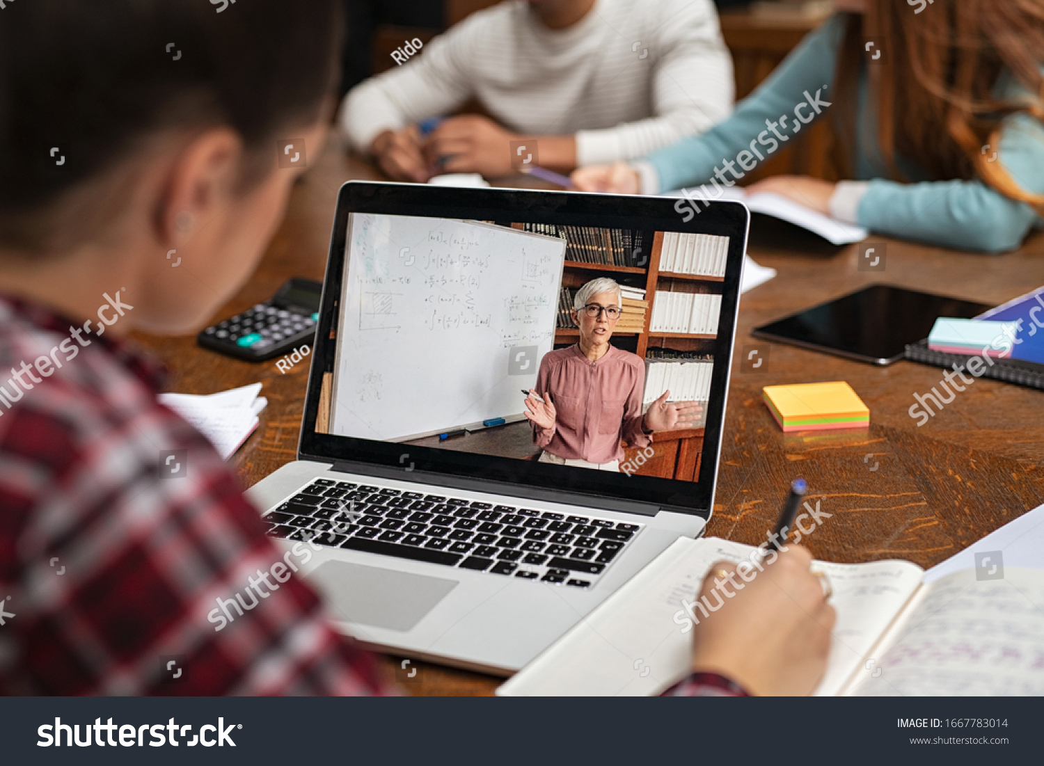 Teacher explaining lesson in video call while girl taking notes. Rear view of university student understanding concepts online while making notes. Young woman studying on computer and writing on notes #1667783014