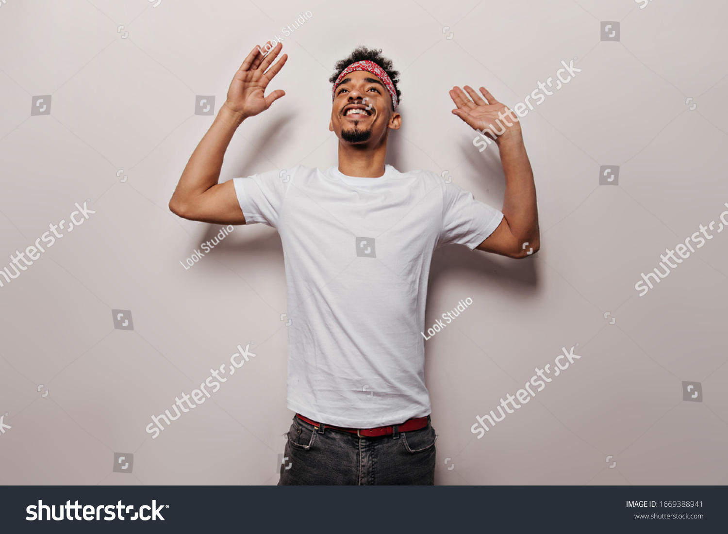 Joyful guy in white T-shirt and black jeans is dancing. Portrait of charming man in tee and pants smiling on isolated background #1669388941