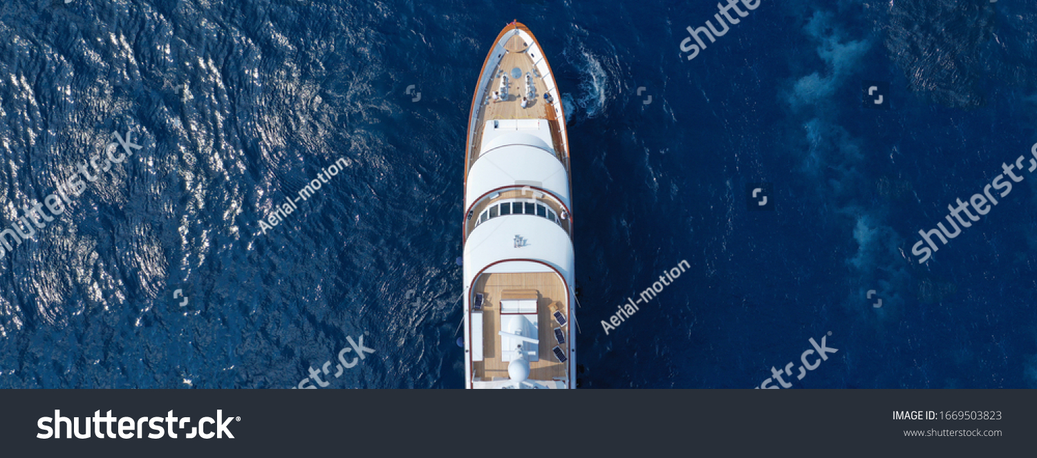 Aerial drone ultra wide top down photo of luxury yacht with wooden deck anchored in Aegean island with deep blue sea, Greece #1669503823