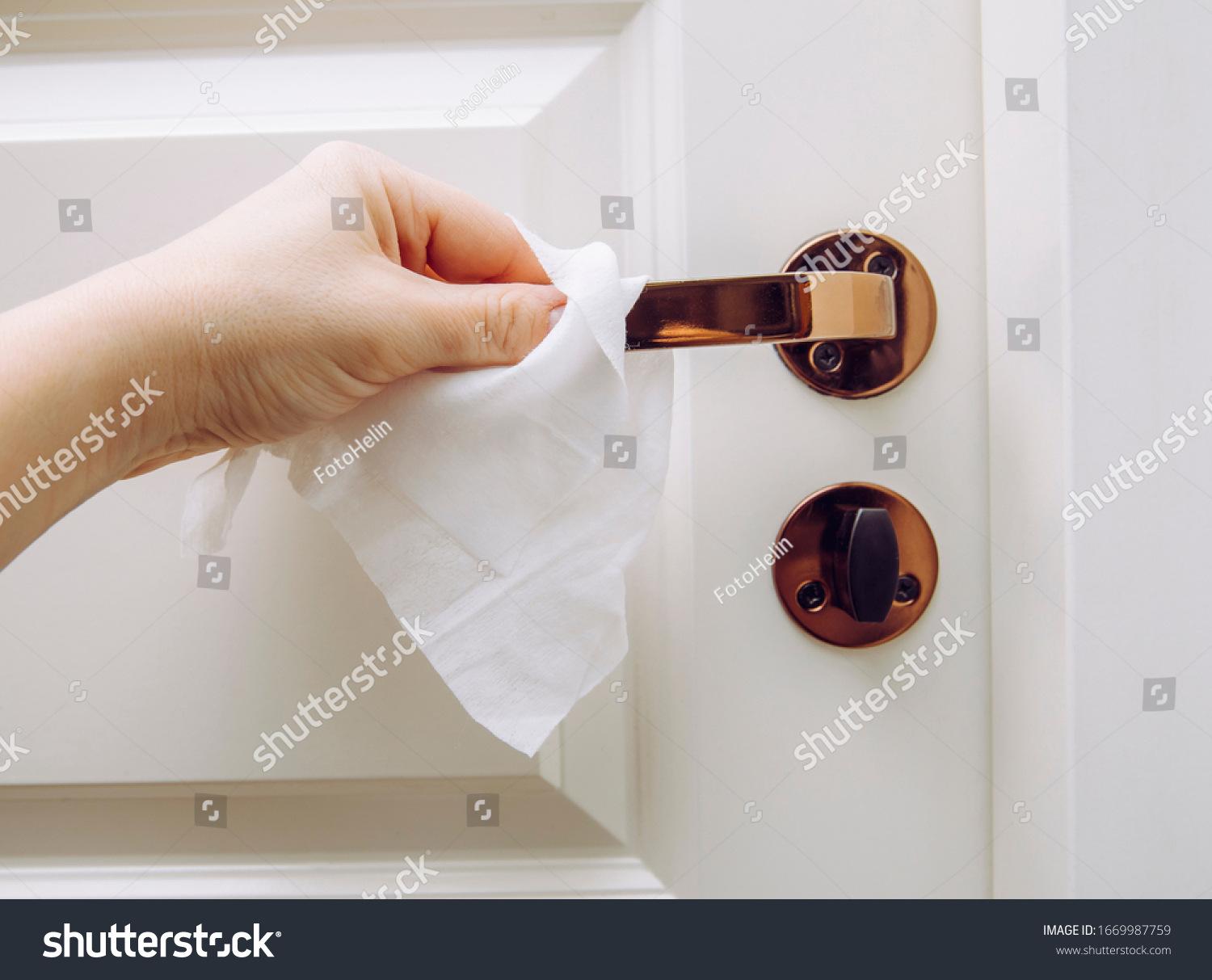 Close up view of woman hand using antibacterial wet wipe for disinfecting home room door link. #1669987759