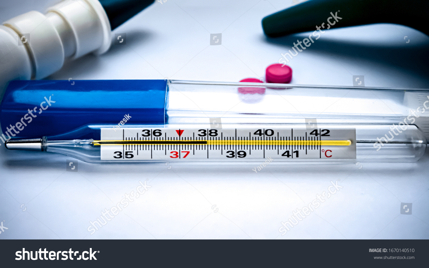 Thermometer which shows high
temperature on the background of tablets and potions. #1670140510