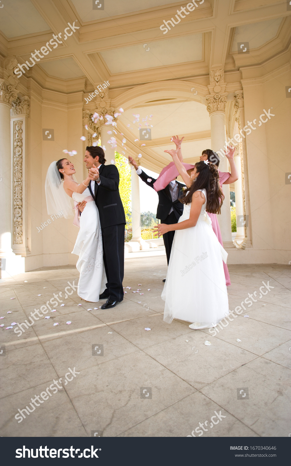 Bride and groom hugging at wedding as guests throw confetti #1670340646