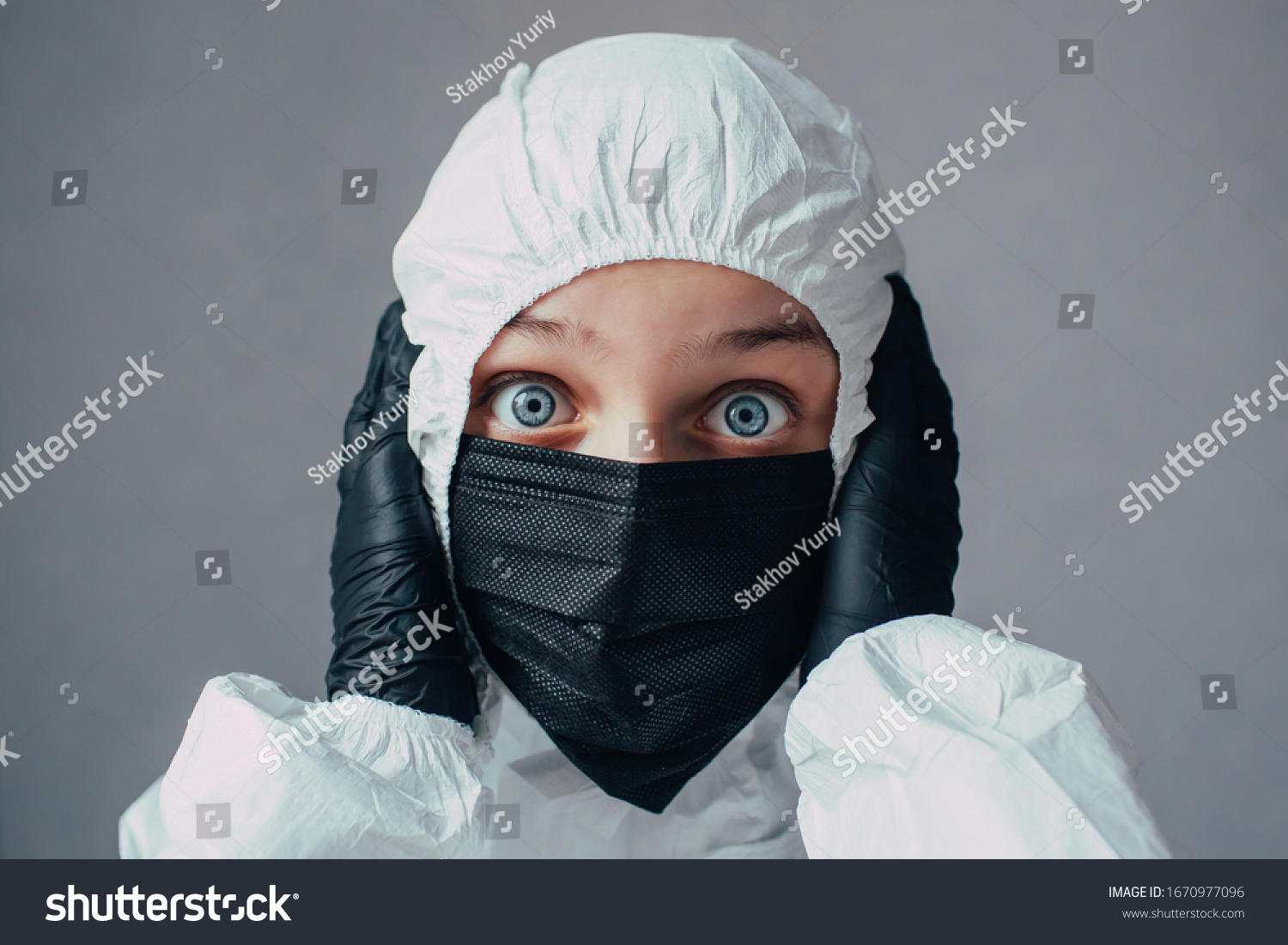 Virologist in black mask in a viral protective suit holds head, looks at the camera with fear and thinking about how to stop the coronavirus epidemic and what to do. Thinks about the dangers of this. #1670977096