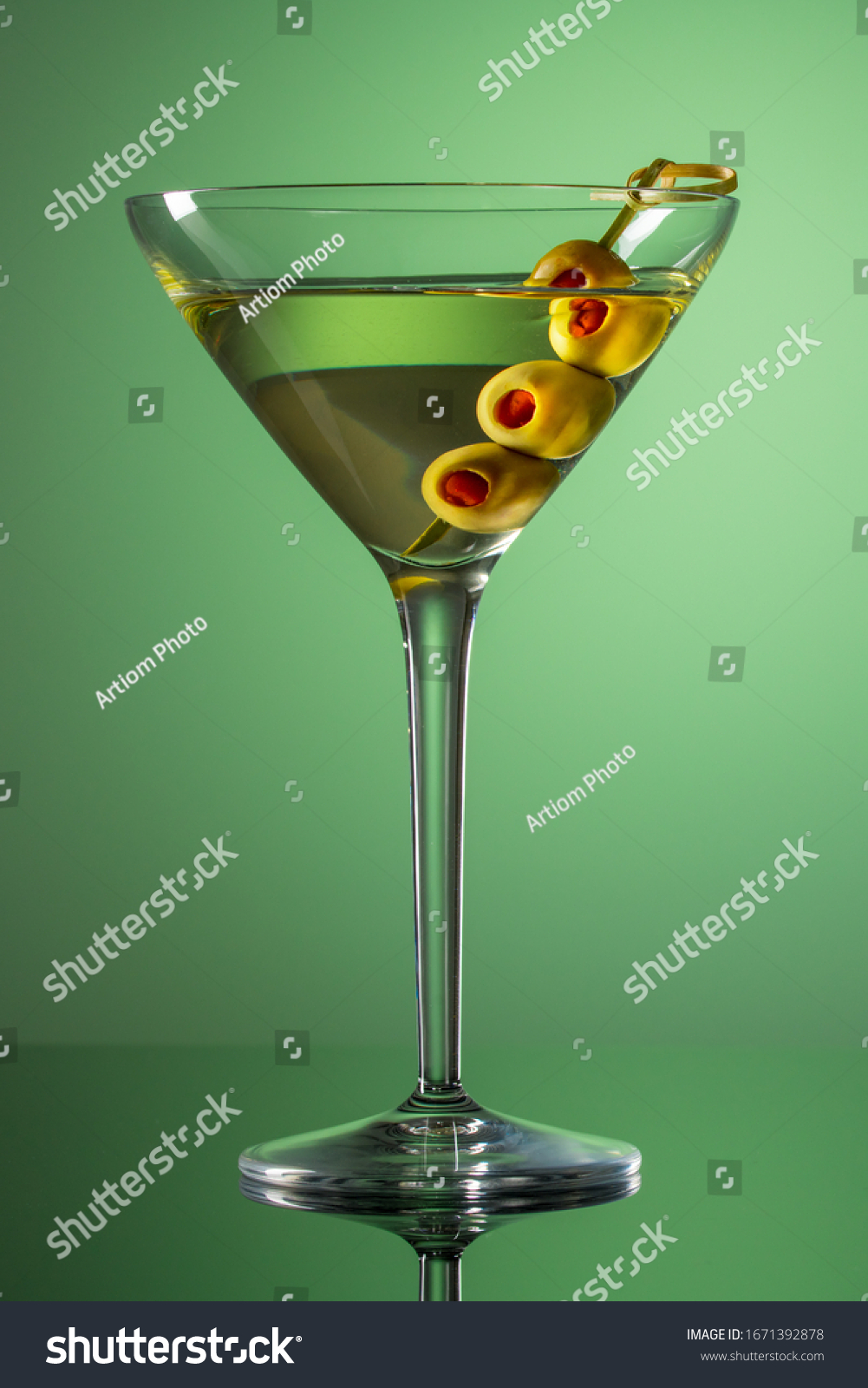 Glass of Martini with olives. Extra dry vermouth martini. Alcohol cocktail on green background.  #1671392878