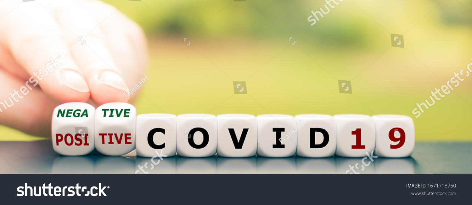 Test result of a Corona test. Hand turns a dice and changes the expression "positive COVID19" to "negative COVID19". #1671718750