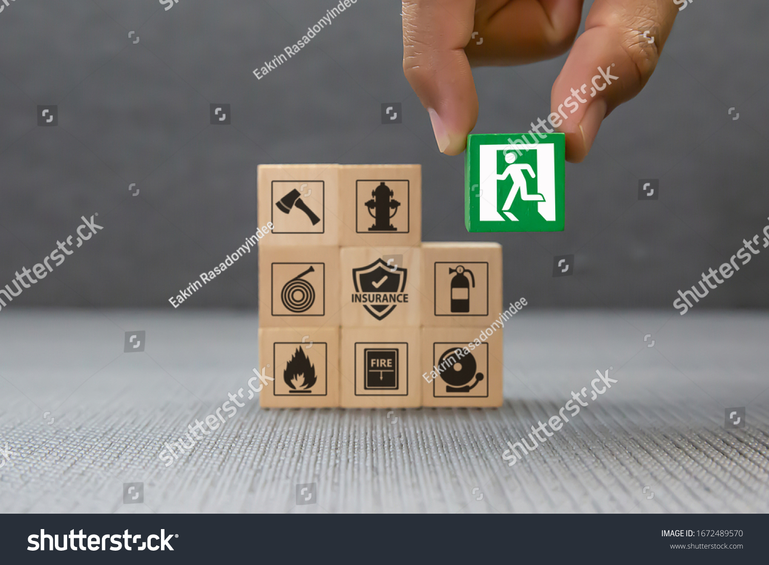 Close-up hand choose a wooden toy blocks with fire exit icon for fire safety protection concepts. #1672489570