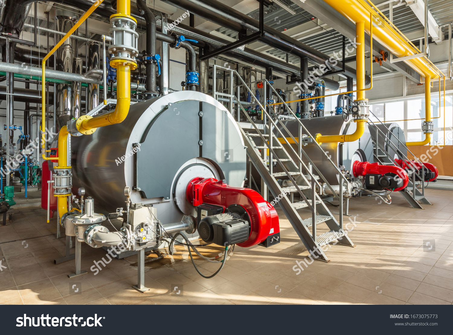 The interior of an industrial boiler room with three large boilers, many pipes, valves and sensors. #1673075773