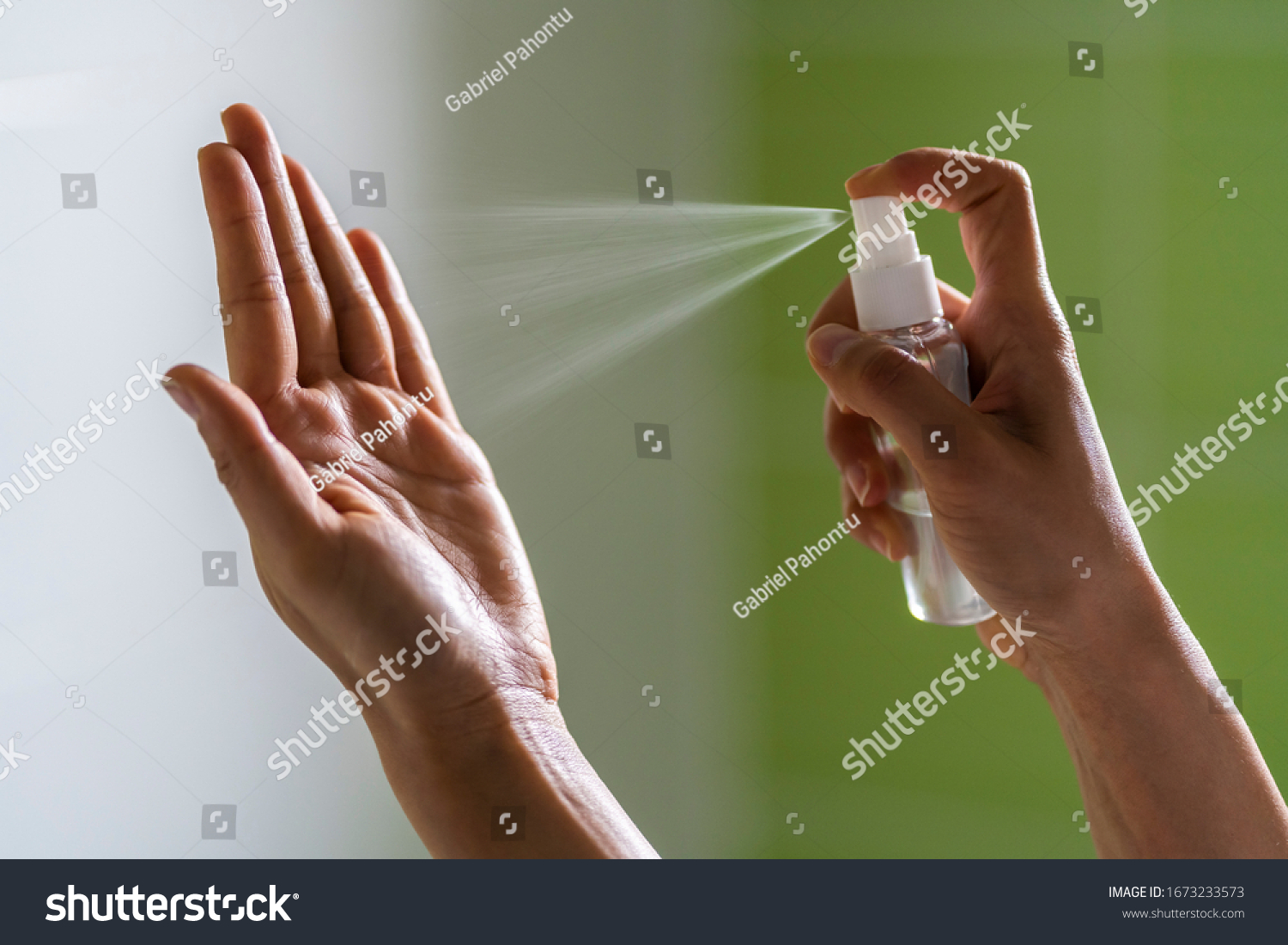 Caucasian woman wipes her hands with an alcohol-based hand-washing spray as a preventive hygiene measure against coronavirus ( Sars-CoV-2, Covid-19) infection. Antibacterial hand sanitizer gel. #1673233573