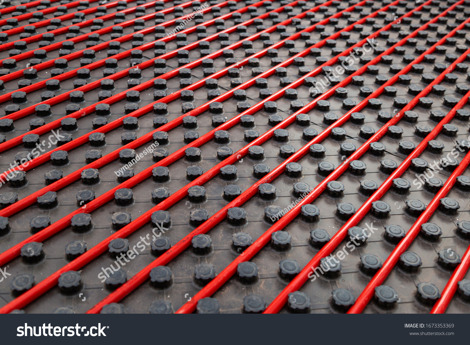Radiant underfloor heating installation with red flexible tubing mounted on black insulation boards #1673353369