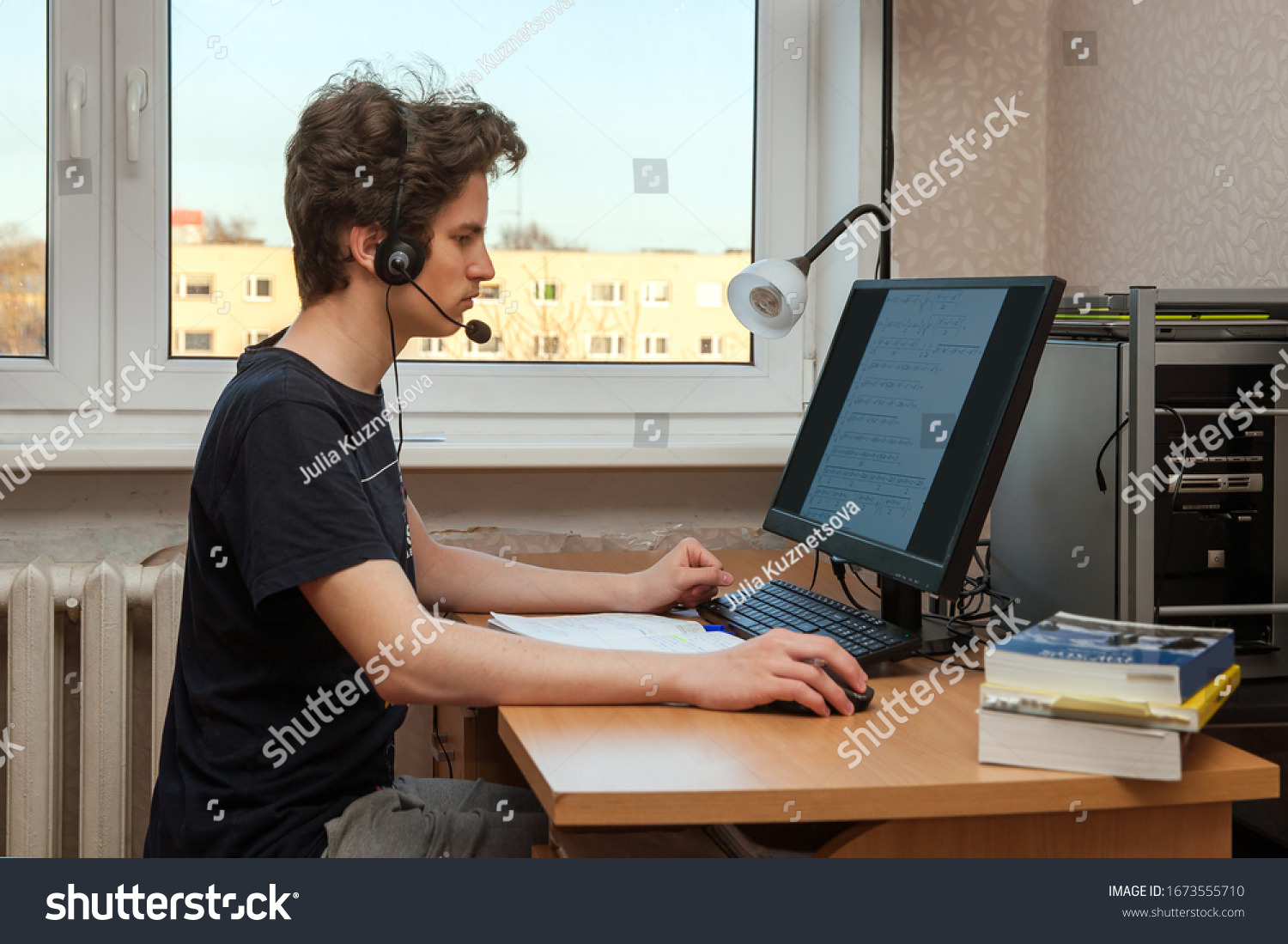 A caucasian teenager studies at home using a PC and headset #1673555710