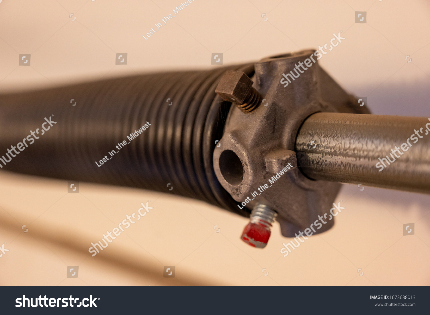 Close up side view of garage door coiled spring #1673688013