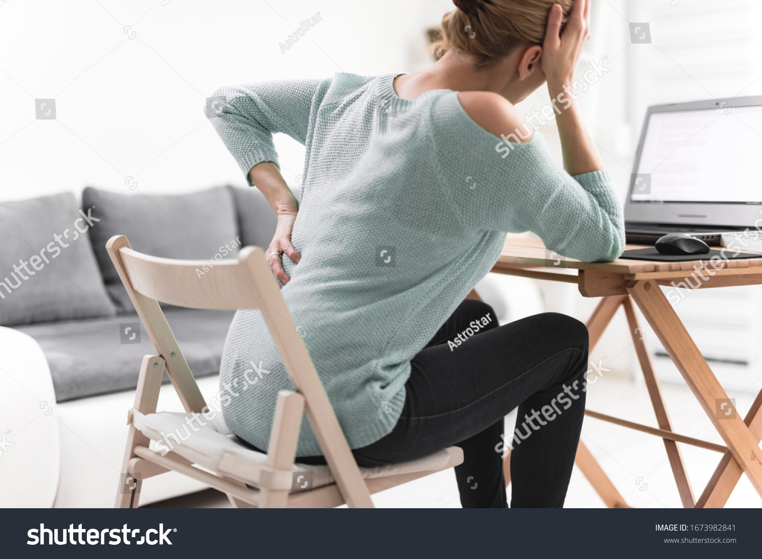 Woman working on a laptop and having headache and back, hip, spine pain. #1673982841