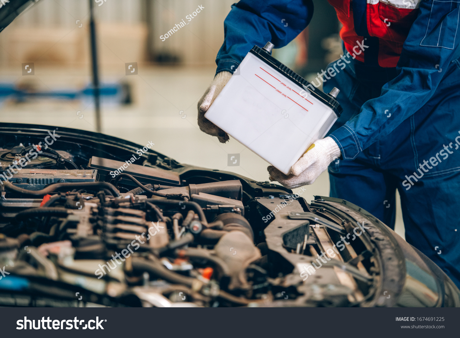 Male mechanic changing car battery, engineer is replacing car battery because car battery is depleted. concept car maintenance #1674691225