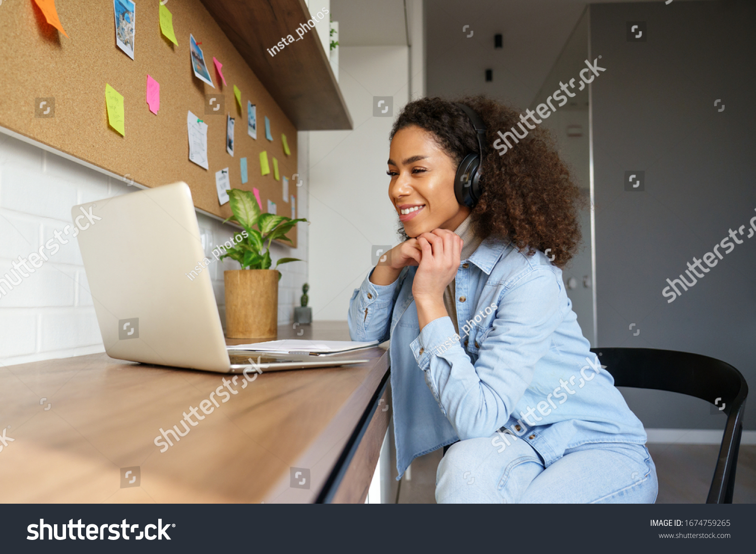Smiling young african american teen girl wear headphones video calling on laptop. Happy mixed race pretty woman student looking at computer screen watching webinar or doing video chat by webcam. #1674759265