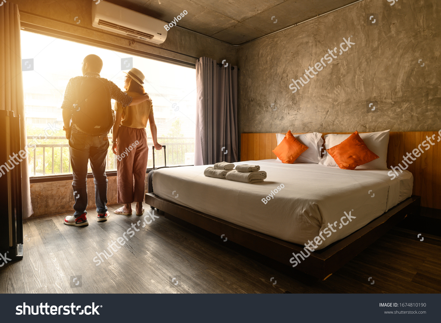 Portrait of young couple tourist standing nearly window, looking to beautiful view outside in hotel/resort bedroom after check-in. Conceptual of couple travel and vacation in their honeymoon period. #1674810190