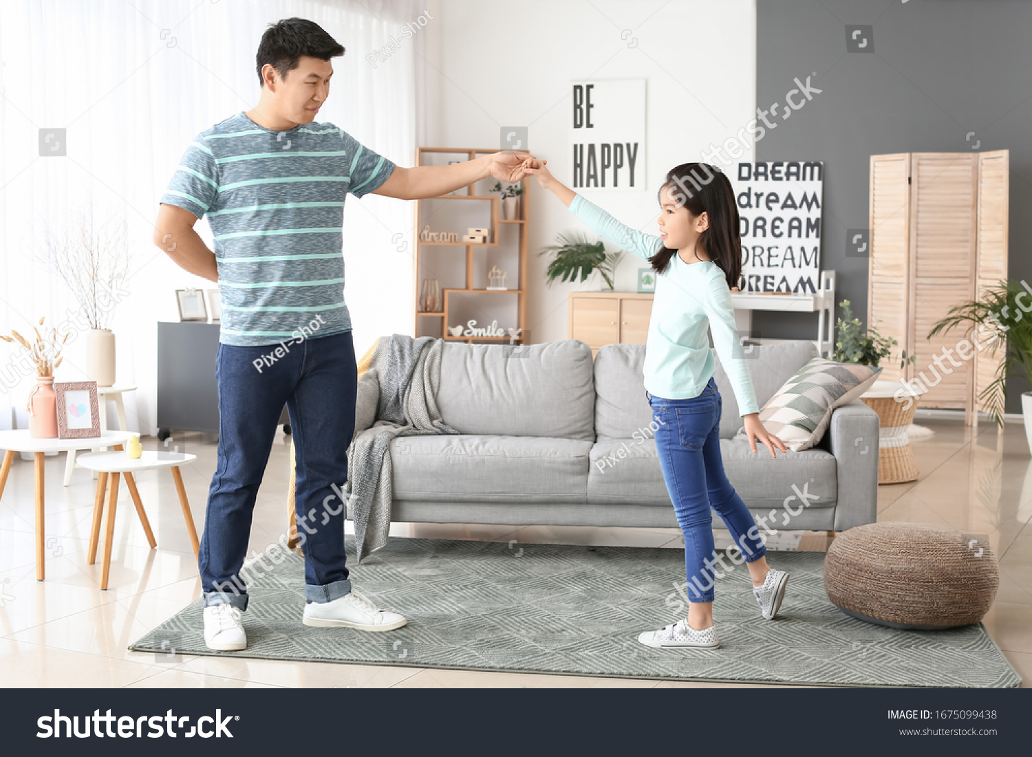 Happy Asian man and his little daughter dancing at home #1675099438