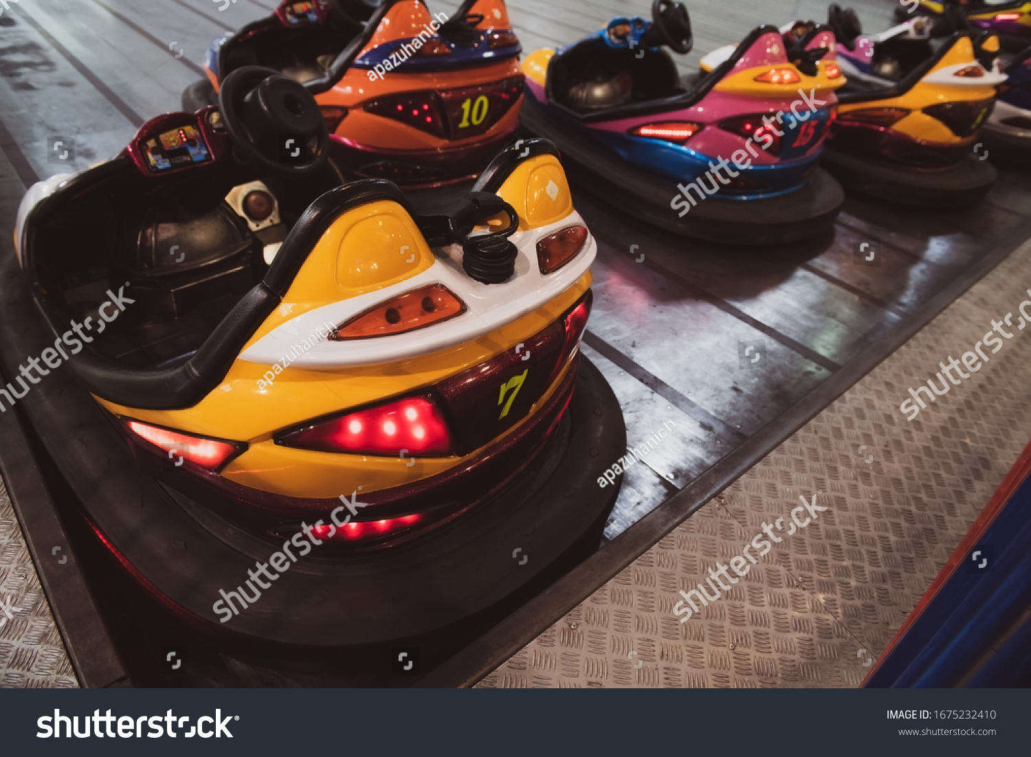 Empty bumper cars with glowing lights at the amusement park. Fairground with attractions. Colorful dodgems. #1675232410