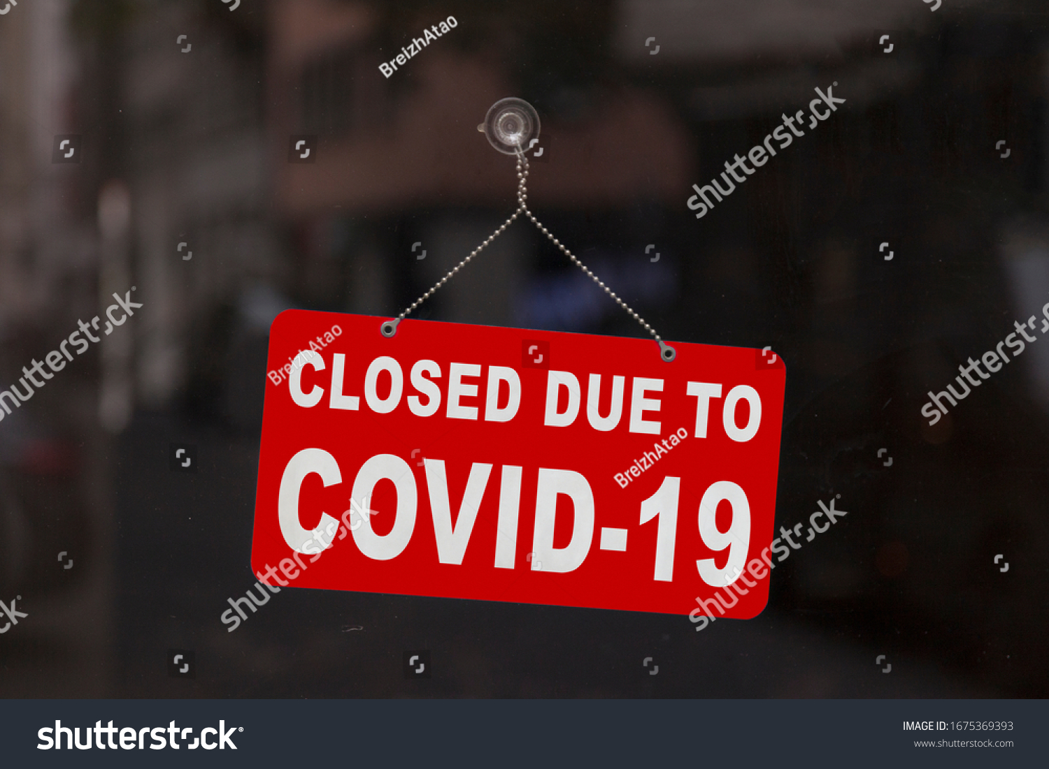 Close-up on a red closed sign in the window of a shop displaying the message "Closed due to Covid-19". #1675369393