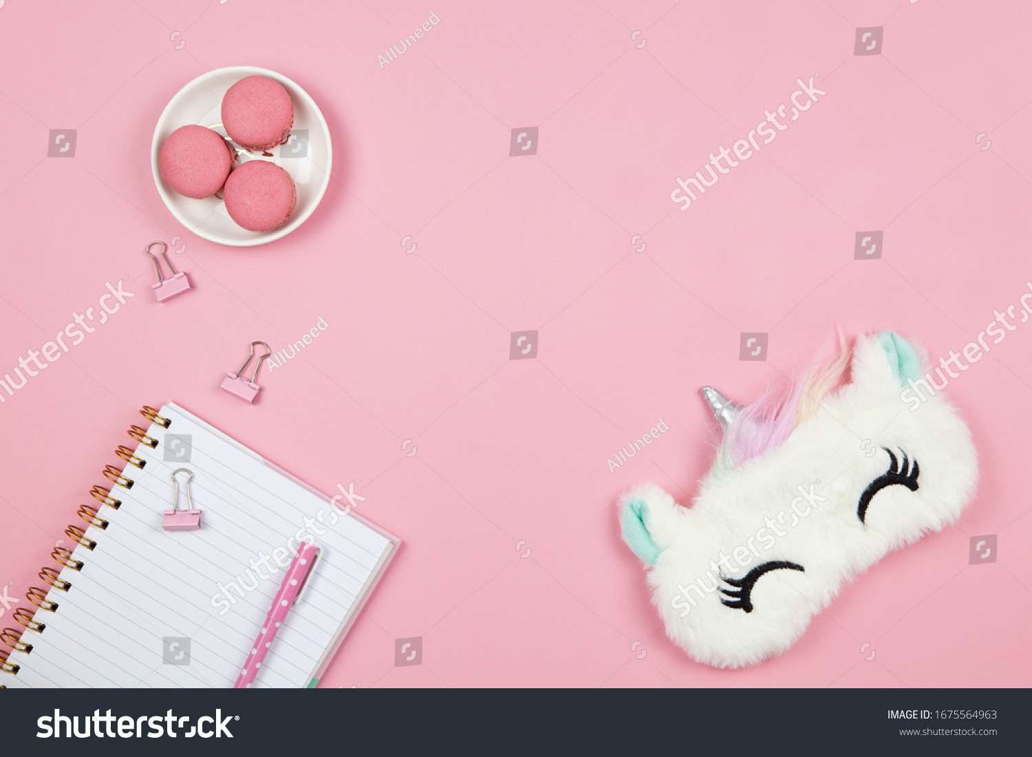 Modern female working space, top view. Cute women's or girls things, slleep mask, macarons, notepad, pen, clamps on pink backround, copy space, flat lay. Work from home concept. For blog. Horizontal. #1675564963
