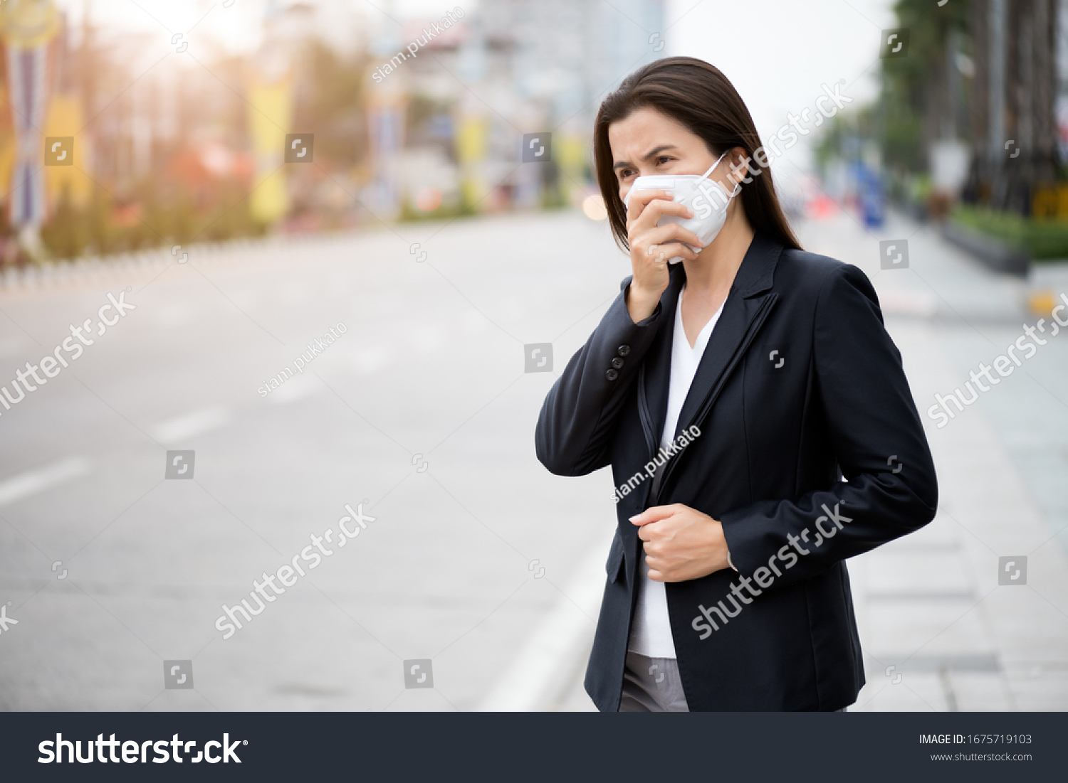 Close up of a businesswoman in a suit wearing Protective face mask and cough, get ready for Coronavirus and pm 2.5 fighting against beside road in background. #1675719103