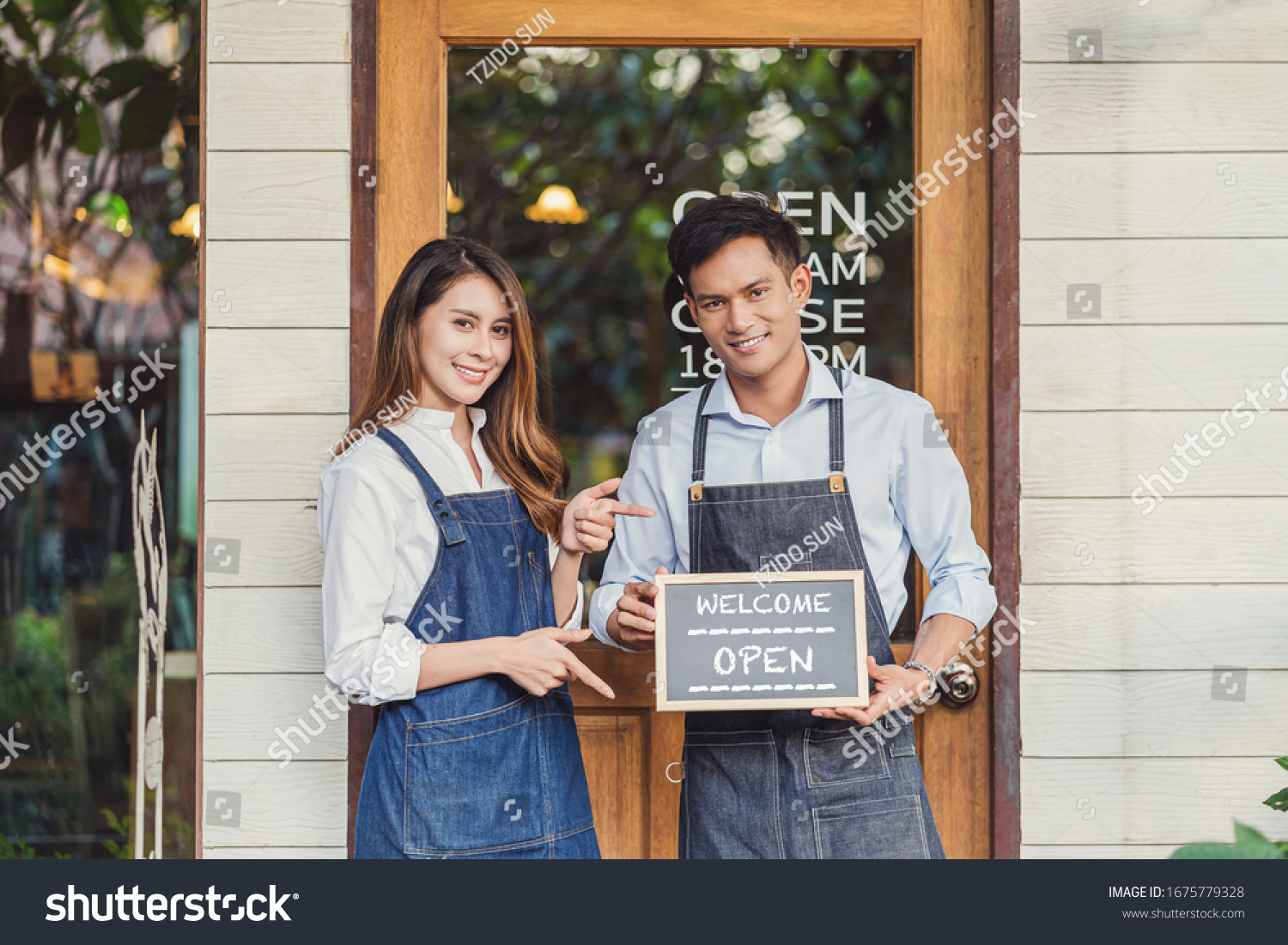 Closeup Asian partner Small business owner hands holding and showing the chalkboard with Welcome Open sign in front of coffee shop, startup with cafe store, installing open and close label concept #1675779328