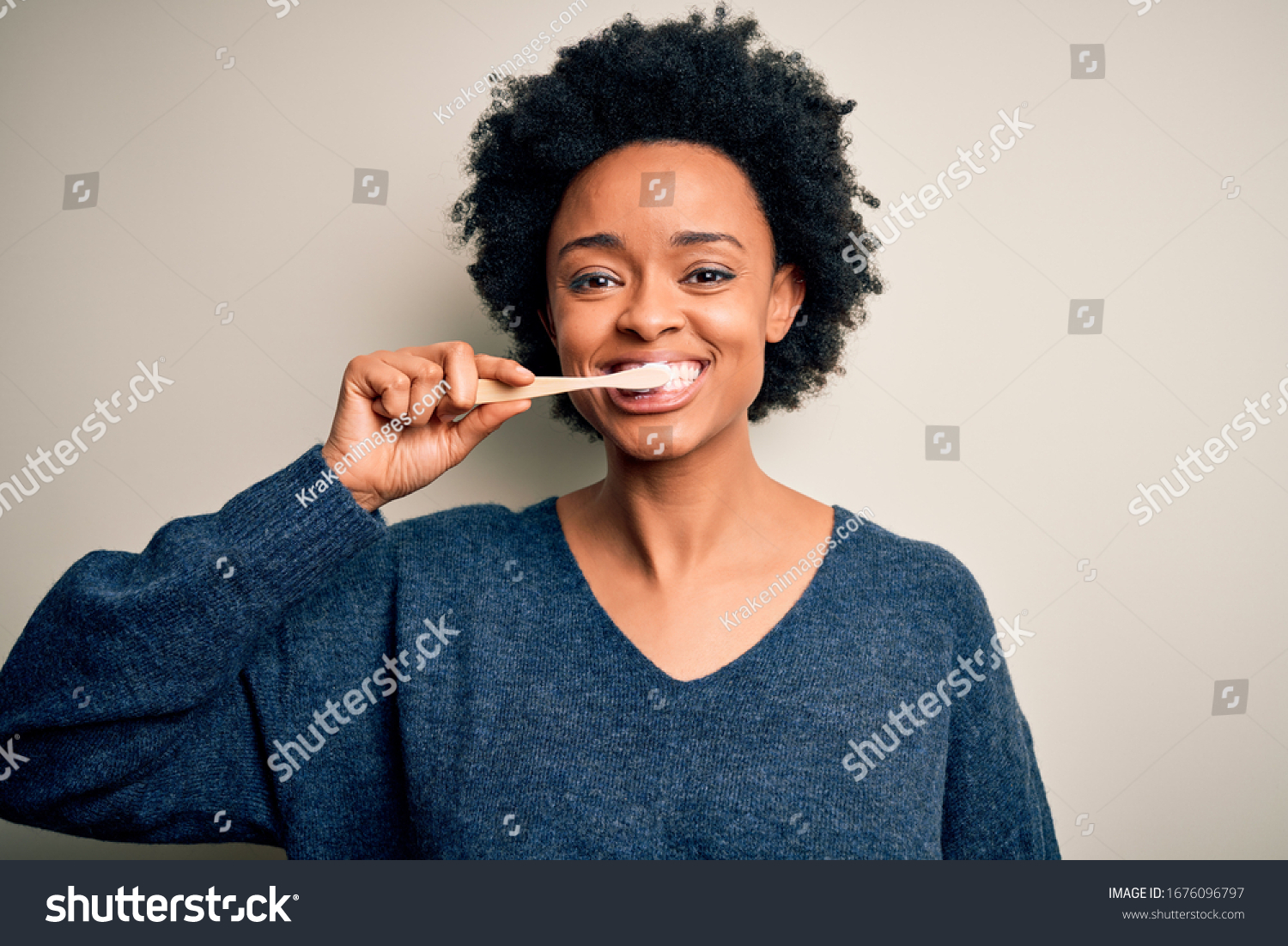 African american woman brushing her teeth using tooth brush and oral paste, cleaning teeth and tongue as healthy health care morning routine #1676096797