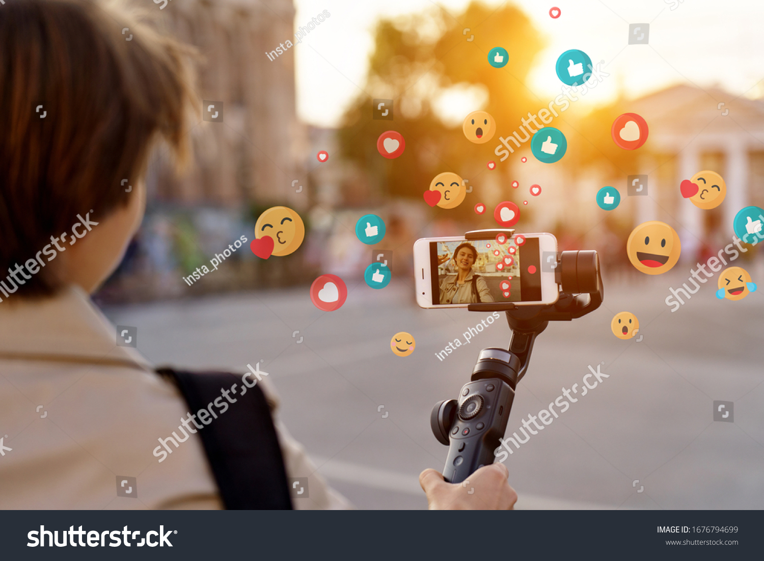 Teen girl blogger vlogger record vlog streaming video hold phone on selfie stick in urban city. Young female vlogger shoot social media blog on smartphone get likes emoji, over shoulder closeup view. #1676794699
