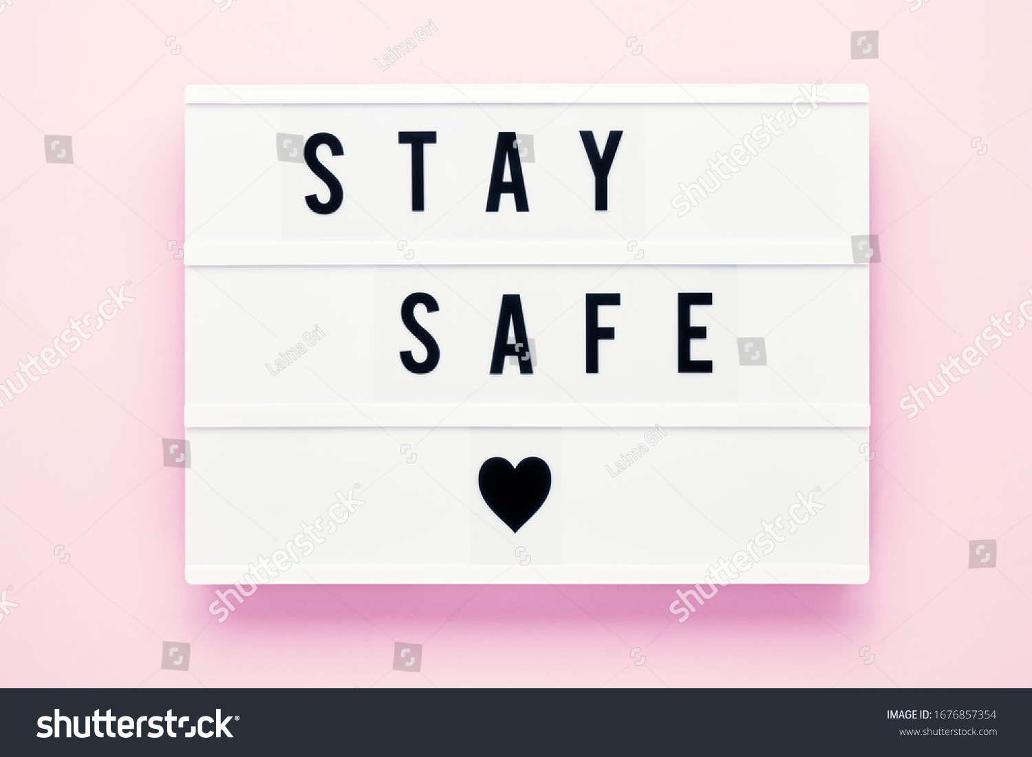 STAY SAFE written in light box on pink background. Healthcare and medical concept. Top view, copy space. Quarantine concept. #1676857354
