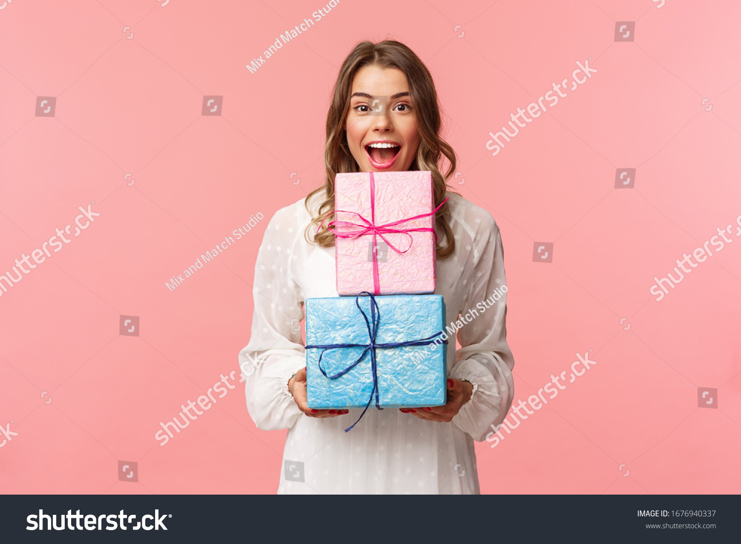 Holidays, celebration and women concept. Portrait of happy cheerful girl likes celebrating birthday and receive presents, holding two gift boxes and smiling camera, pink background #1676940337