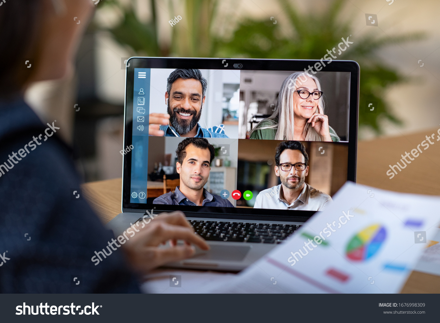Back view of business woman talking to her colleagues about plan in video conference. Multiethnic business team using laptop for a online meeting in video call. Group of people smart working from home #1676998309
