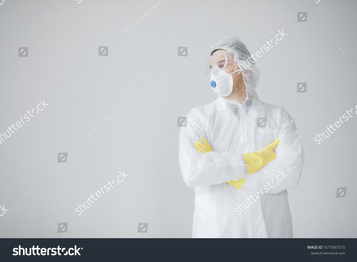 Man in white protective suit, mask, glasses and gloves is coughing on white background, coronavirus pandemic threat. Epidemic, pandemic of coronavirus covid 19. Doctor, patient in respirator. #1677067315
