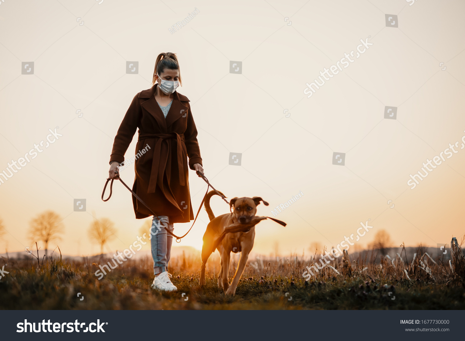 Woman wearing a protective mask is walking alone with a dog outdoors because of the corona virus pandemic covid-19 #1677730000