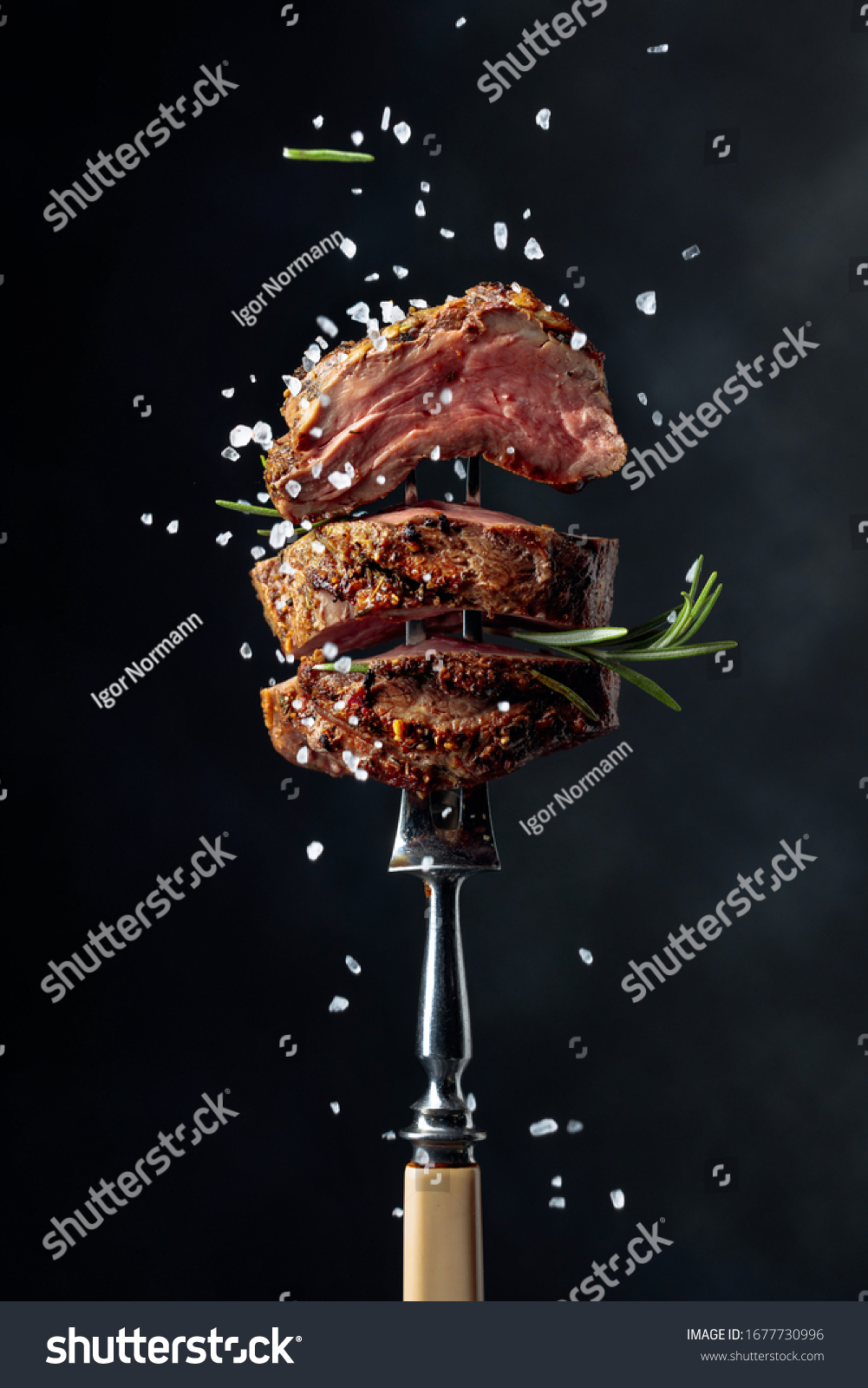 Grilled beef steak with spices on a black background. Beef steak on a fork sprinkled with rosemary and sea salt.    #1677730996
