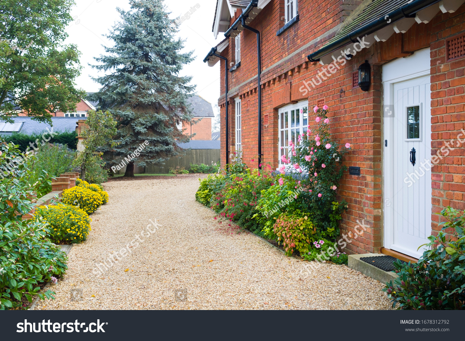 English country house and garden in Autumn with a gravel driveway. The house is Victorian period, with flower borders filled with shrubs and perennials #1678312792
