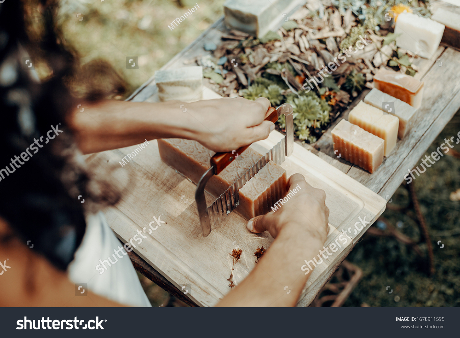 Woman is making handmade natural soaps on an old wooden table #1678911595