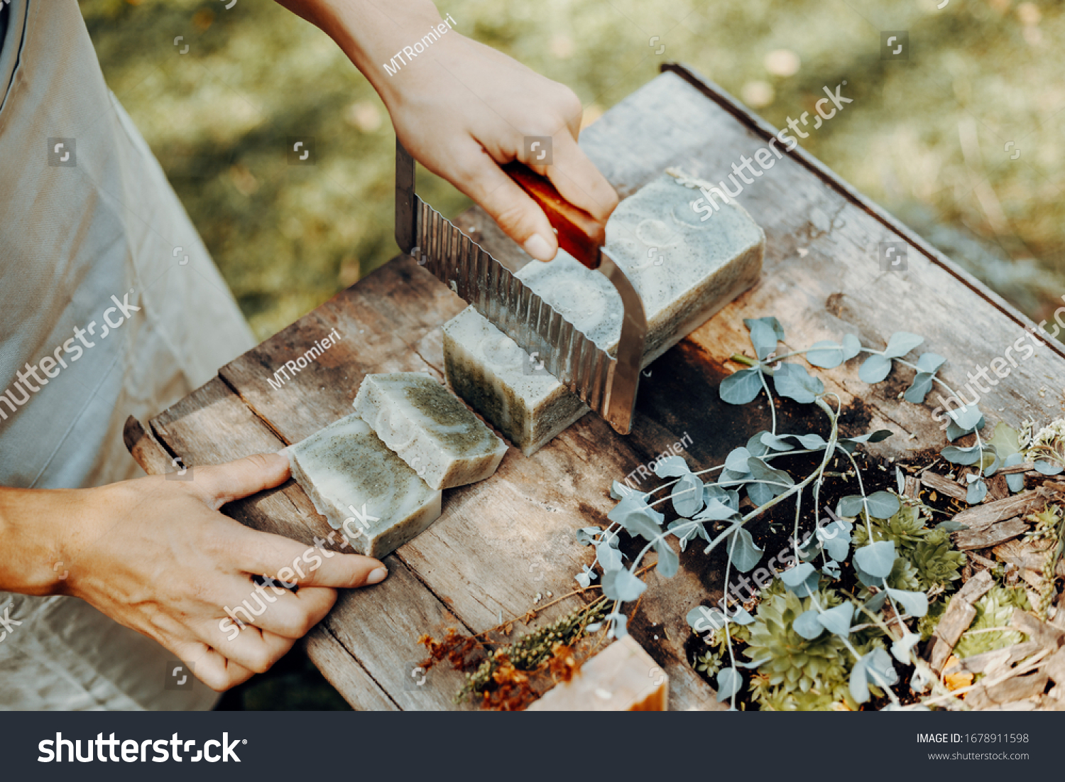 Woman is making handmade natural soaps on an old wooden table #1678911598