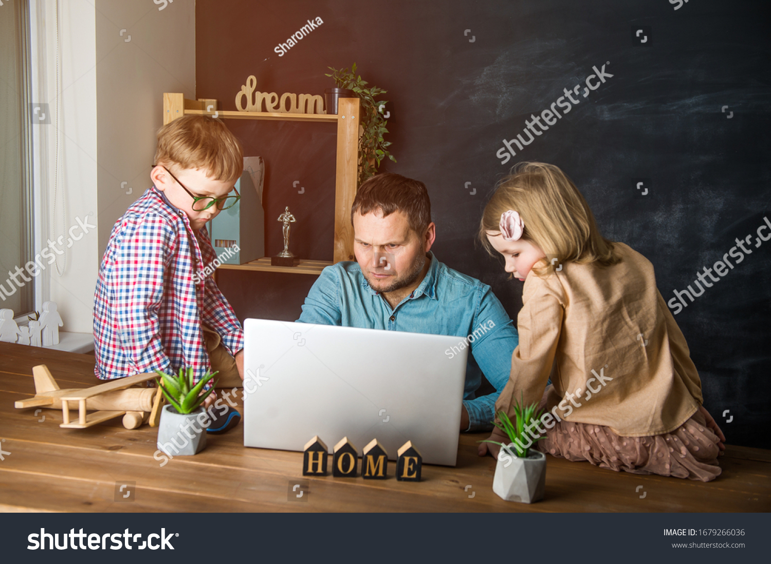 Work from home on laptop. Father and children boy and girl sitting on the table.  #1679266036
