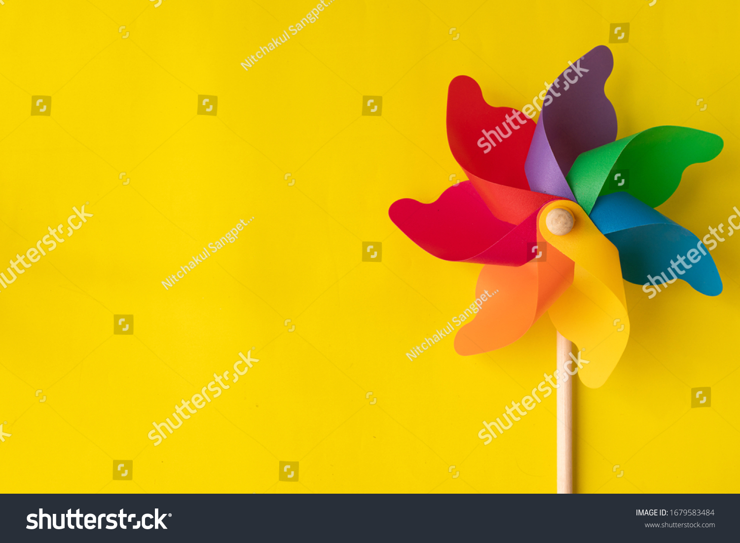 Flat lay Rainbow pinwheel on yellow background, copy space. #1679583484