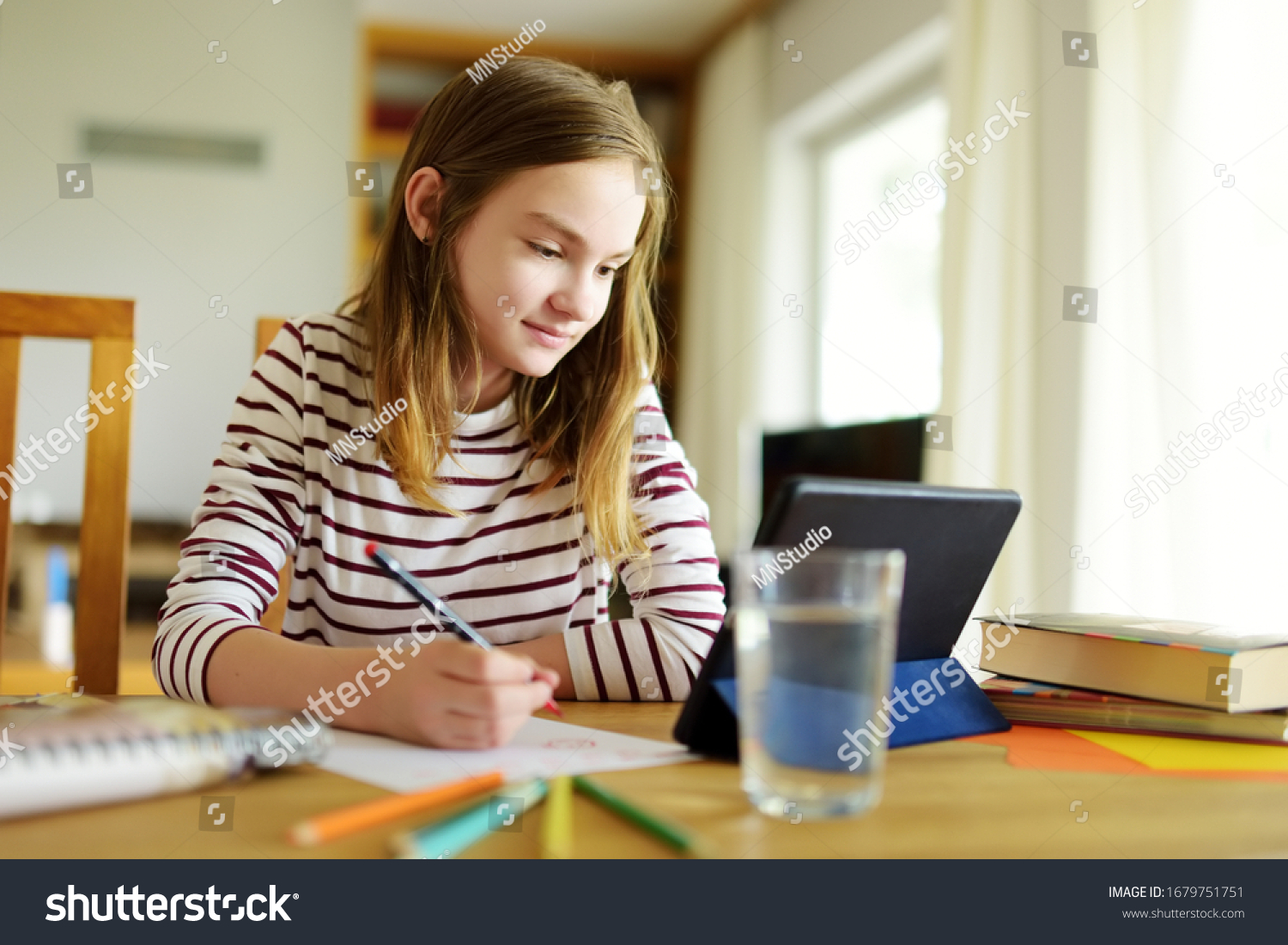 Preteen schoolgirl doing her homework with digital tablet at home. Child using gadgets to study. Education and distance learning for kids. Homeschooling during quarantine. Stay at home entertainment. #1679751751
