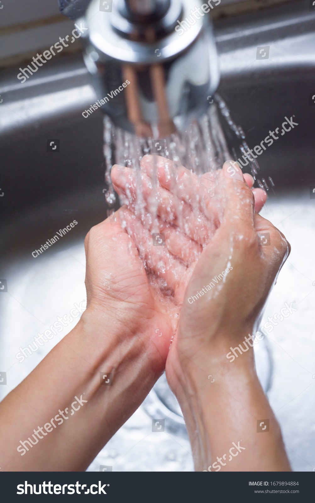 Closeup of handwashing with water at kitchen sink, a prevention measure against Coronavirus #1679894884