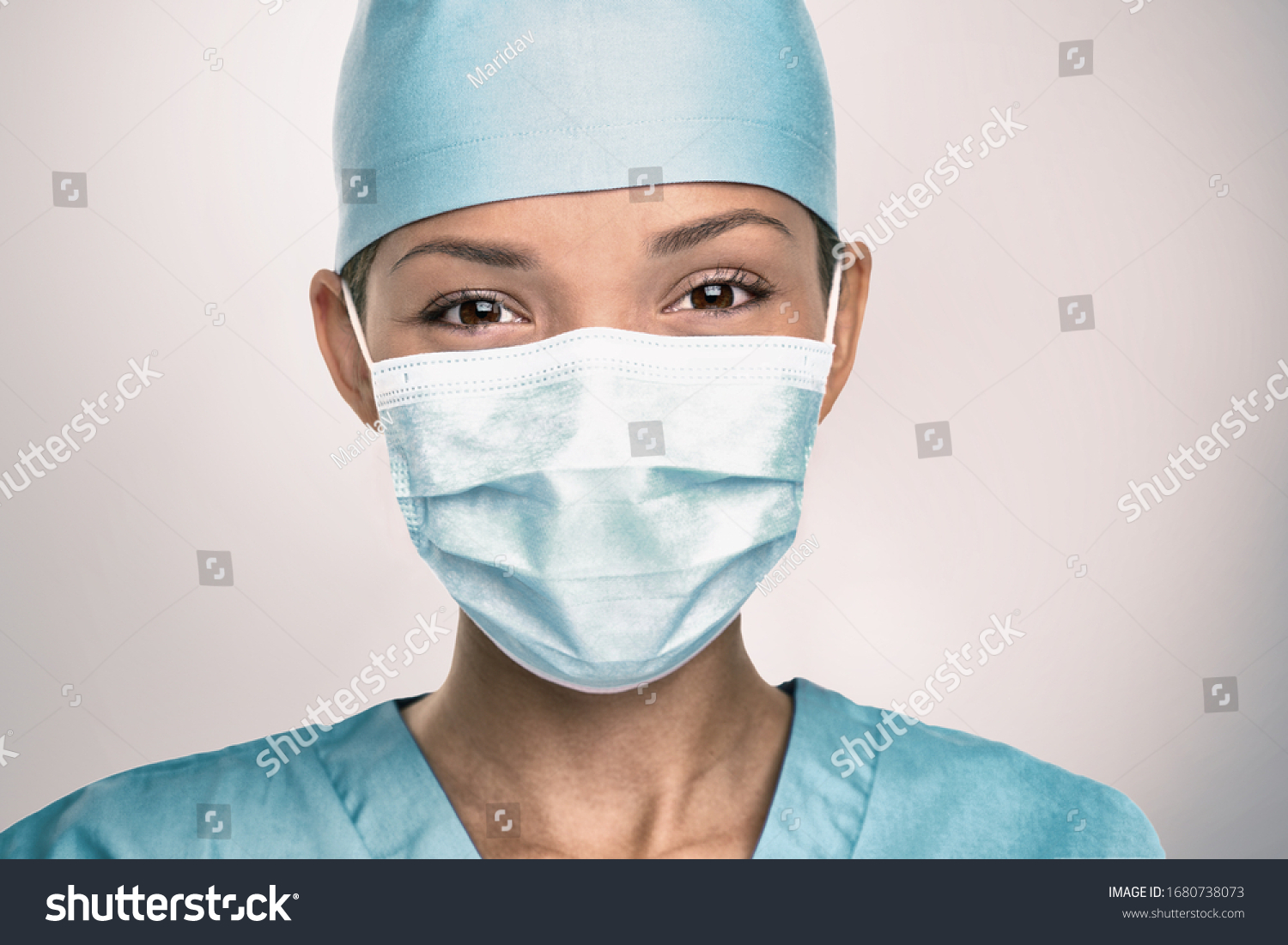 COVID-19 Coronavirus pandemic happy Asian doctor positive with hope wearing surgical mask and blue protective scrubs at hospital. Inspiring confidence in the future to solve the crisis. #1680738073