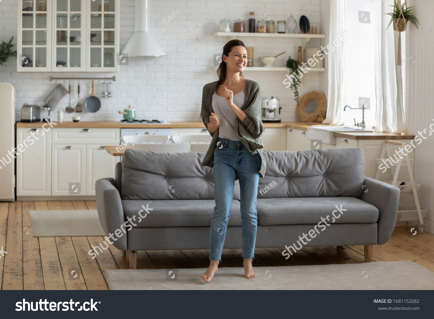 Overjoyed young woman enjoy free leisure weekend at home dancing listen to music in living room, smiling happy millennial female have fun moving to rhythm being active in modern studio home #1681152682