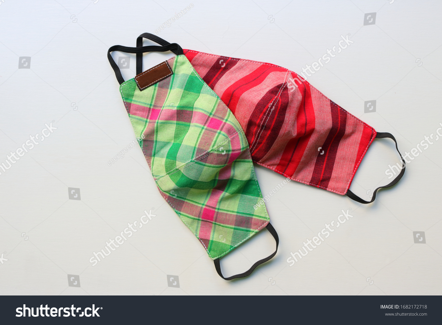 Two handmade face masks made from plaid cloth placed on wooden table, washable and reusable, can be used during shortage of surgical mask due to coronavirus pandemic  