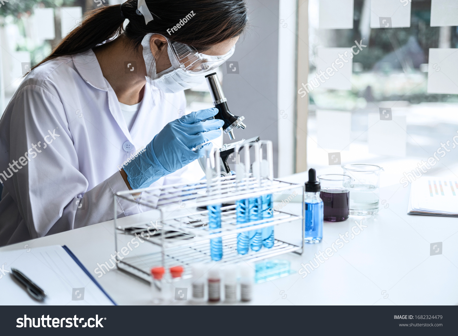 Scientist or medical in lab coat working in biotechnological laboratory, Microscope equipment for research with mixing reagents in glass flask in clinical laboratory. #1682324479