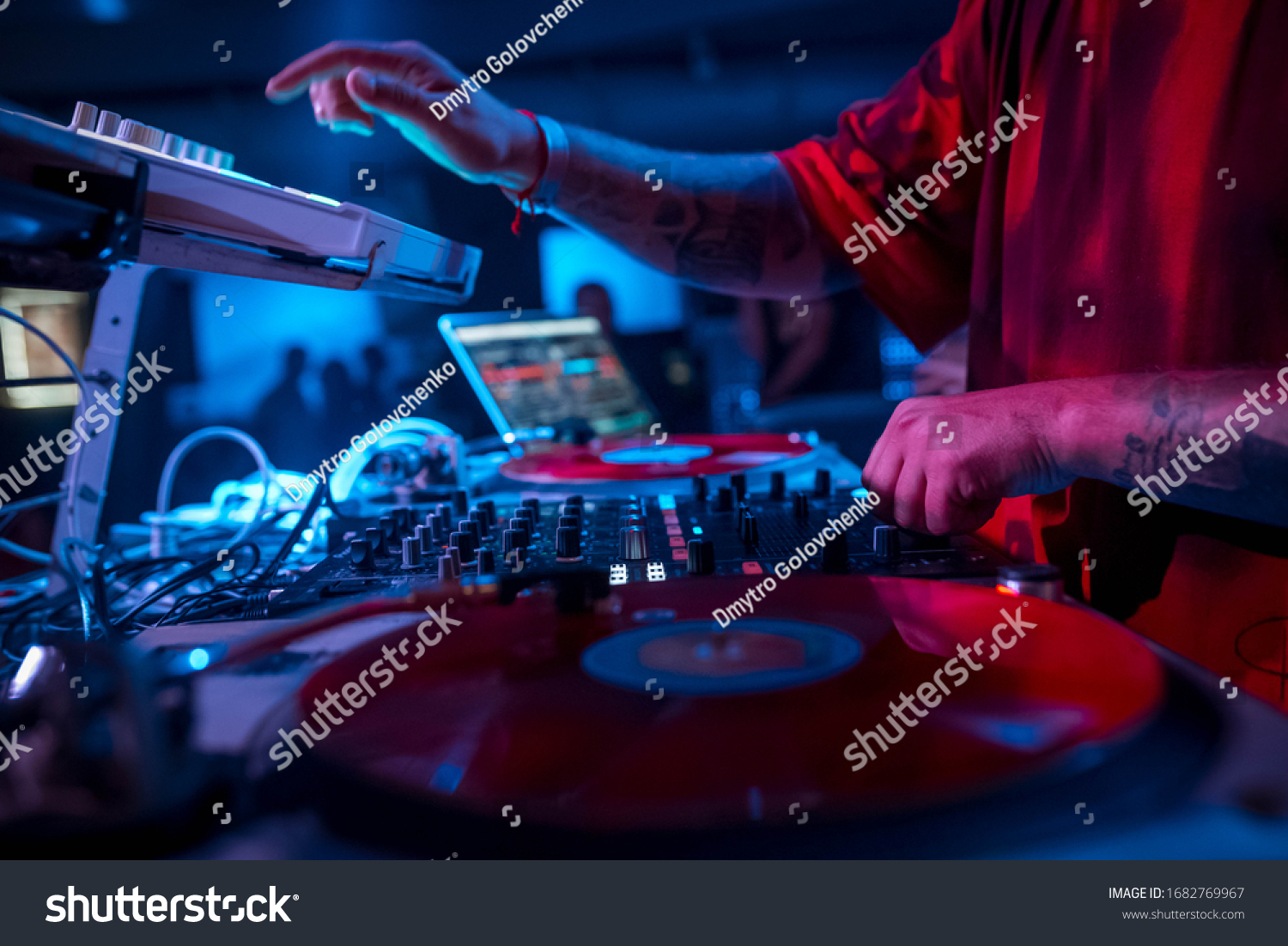 The DJ in the red T-shirt plays on the DJ equipment, play vinyl turntable, on the microbrand console using the controller. disco DJ. night life. atmosphere. club photo #1682769967