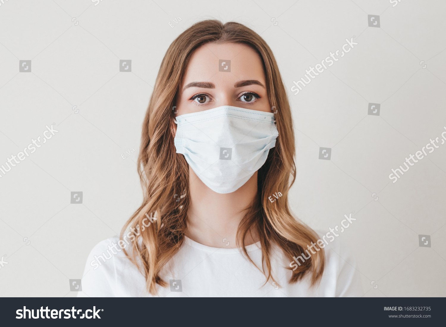 Portrait of a young girl in a medical mask isolated on a white wall background. Young woman patient, copy space #1683232735