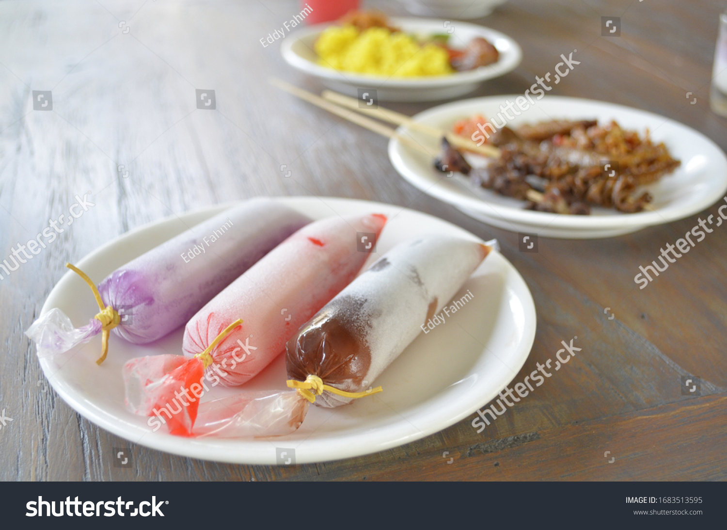 Assorted iced syrup wrapped in plastic tube, served as dessert in traditional javanese restaurant. #1683513595