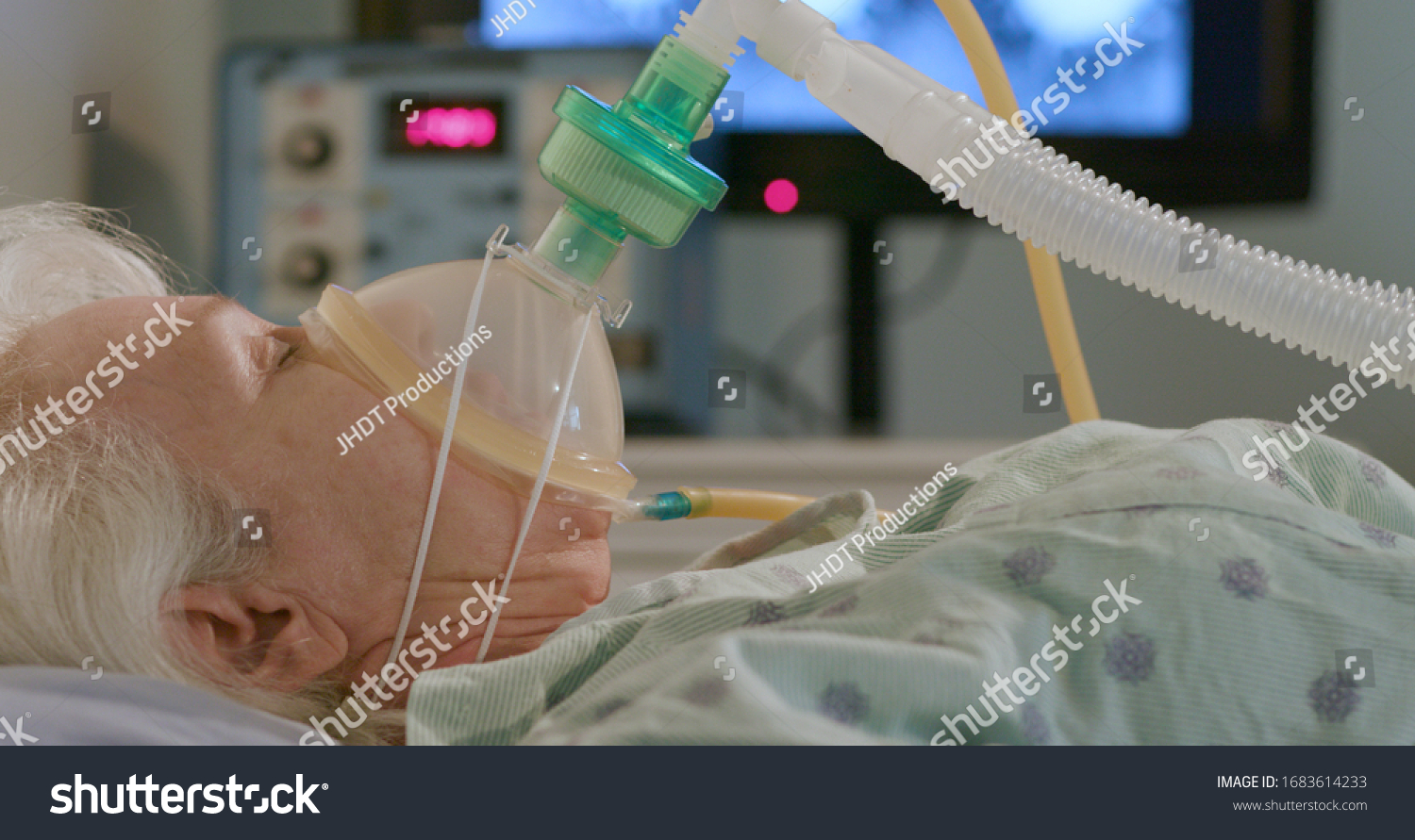 A hospitalized elderly woman attached to a device to help her breathe with an image of the coronavirus in the background. #1683614233